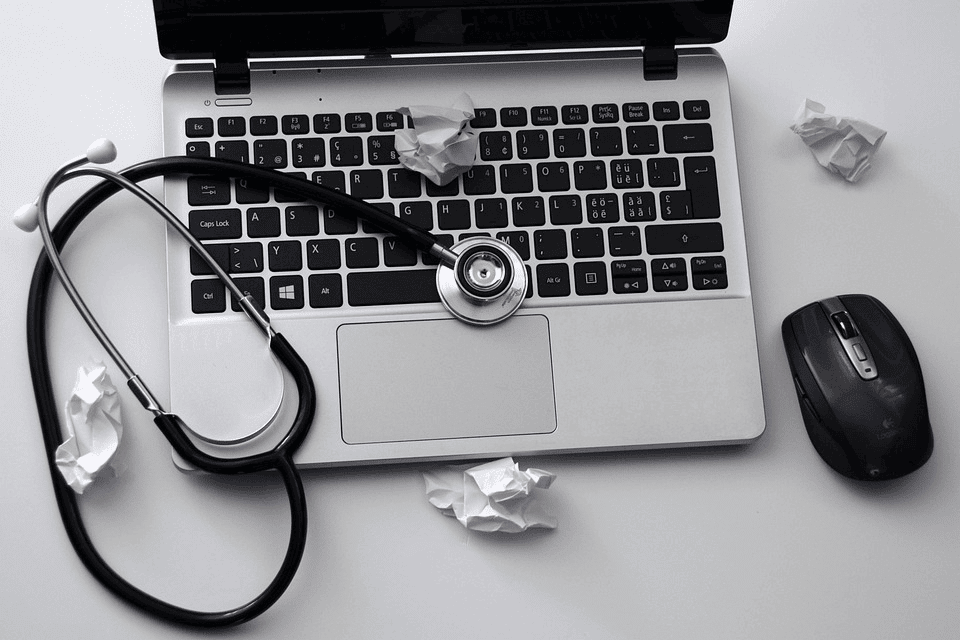 opened laptop with a stethoscope above it as if examining an old PC