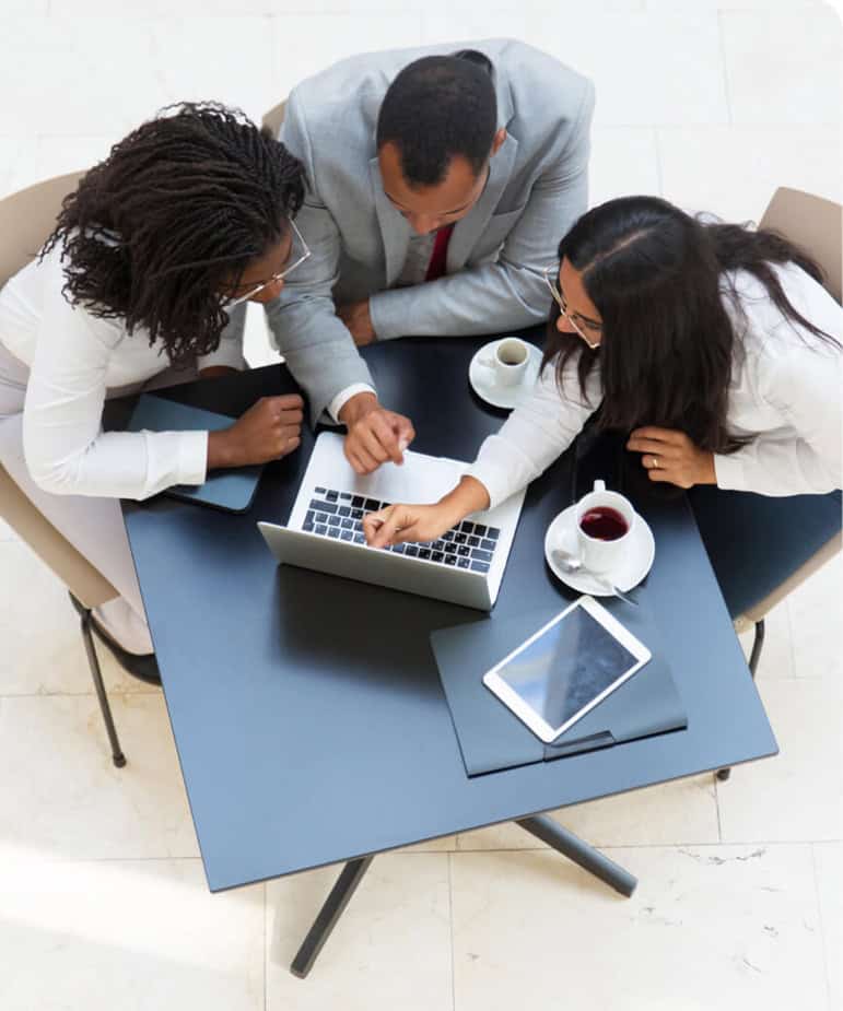 Team discussing in front of a laptop, pointing to the monitor as they collaborate