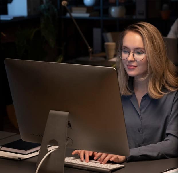 Smiling woman facing a monitor, conveying confidence in her protection from cyberthreats