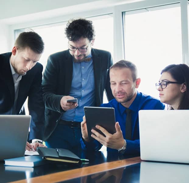 Corporate Team working together in the same table using different devices like laptop, tablet and phone